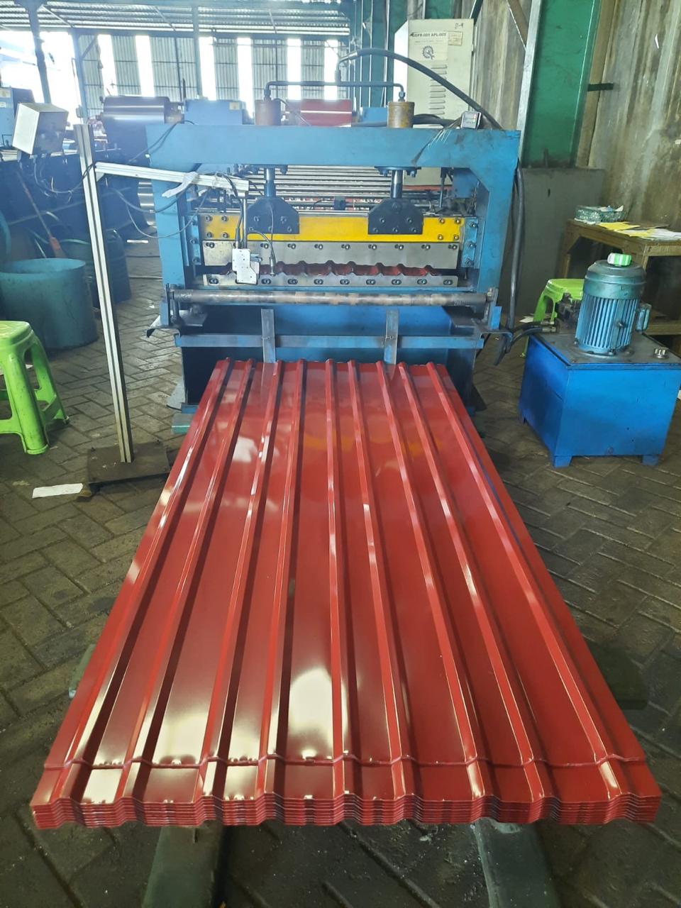 Atap merah keluar dari mesin roll-forming di lini produksi MR Maklon